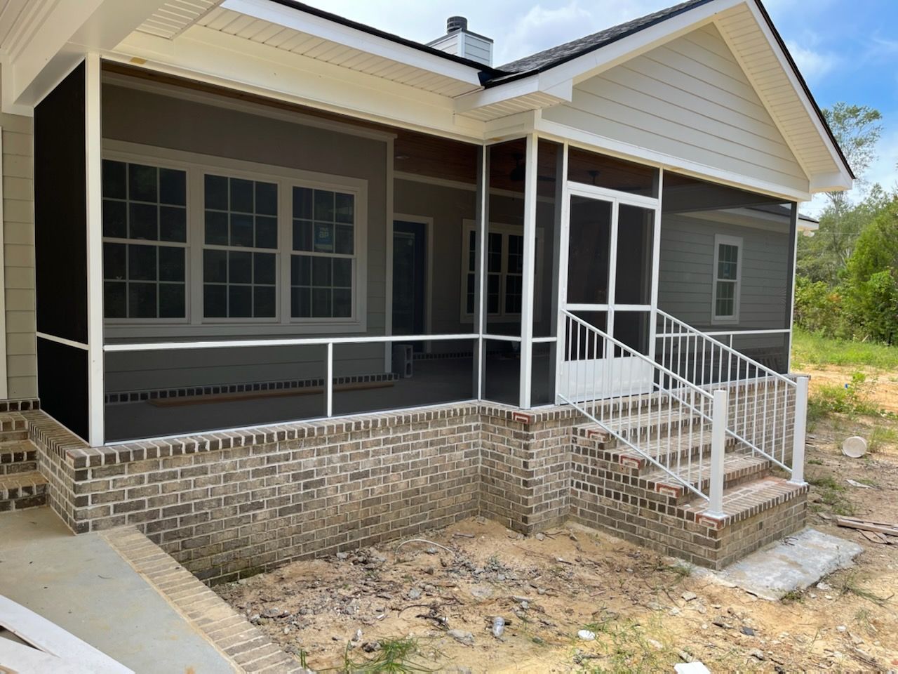 Screened-in porch with brick foundation and steps. White railings and trim, gray siding.