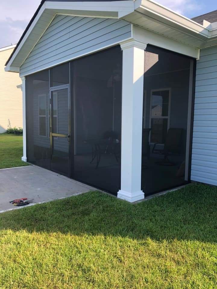 Screened-in porch attached to a light blue house, with concrete patio and green grass.