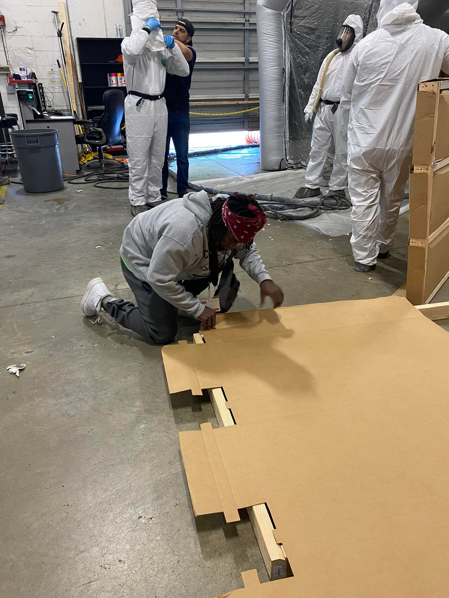 A group of people in protective suits are working on a cardboard box.
