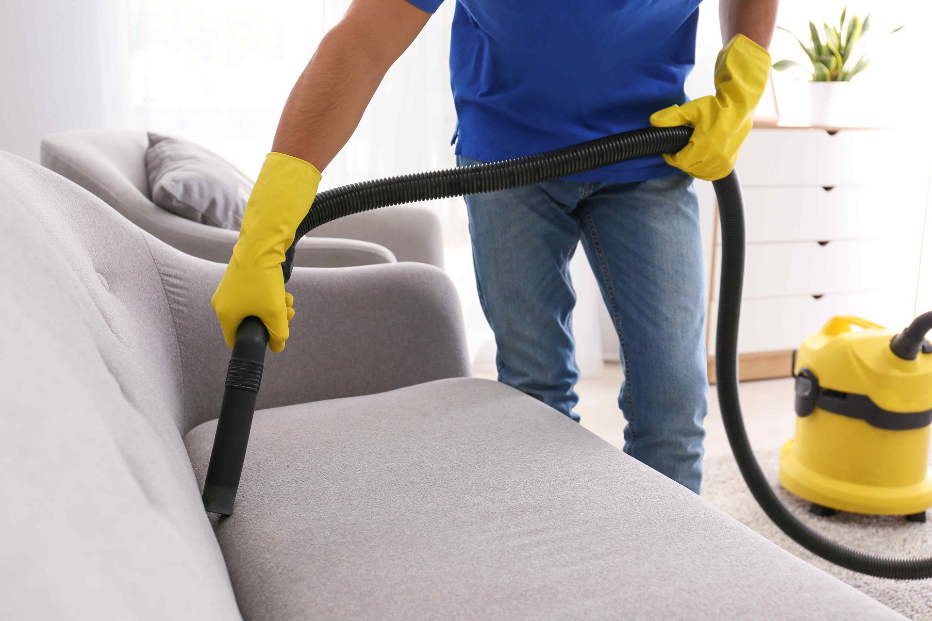 A team member vacuuming between upholstery cushions