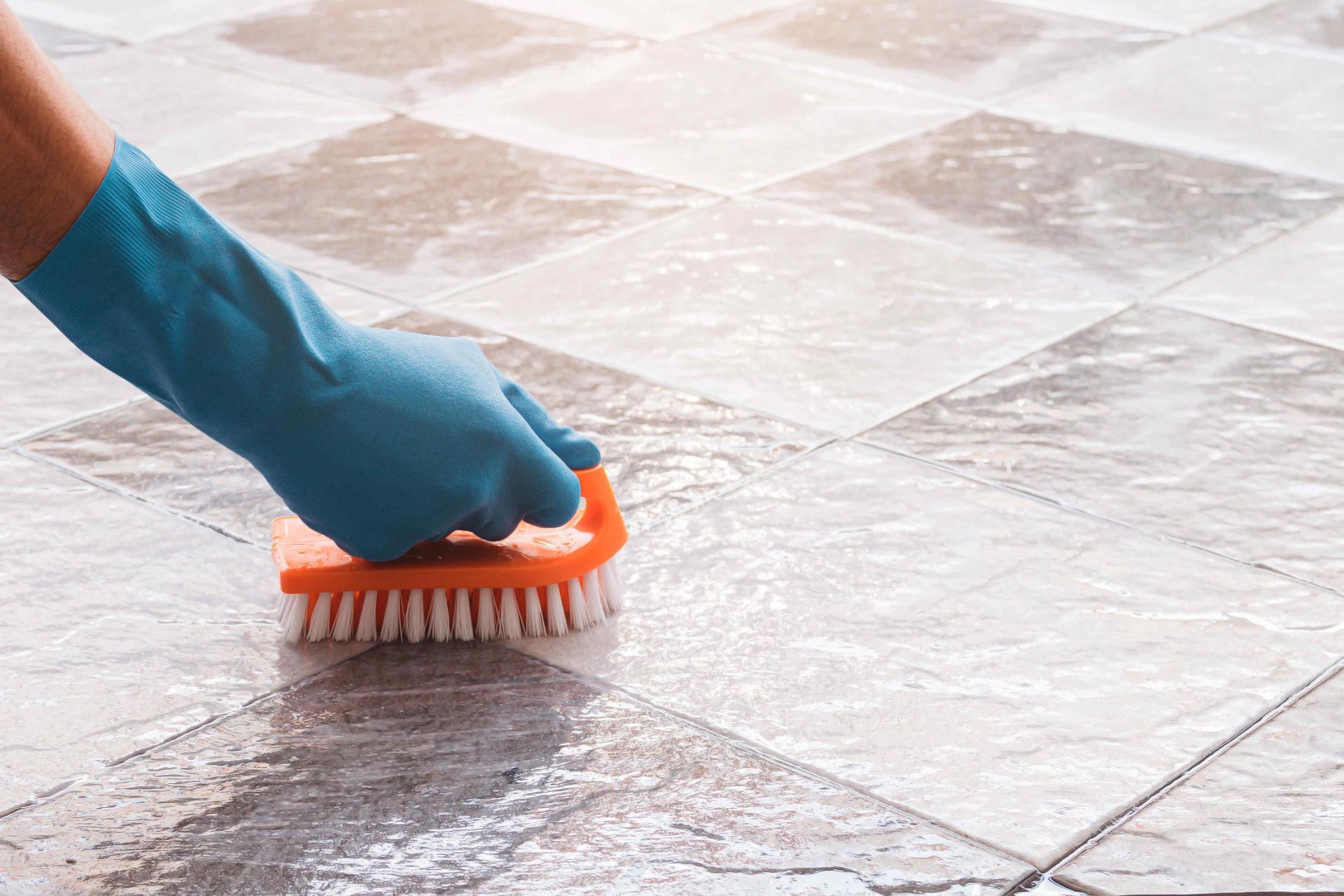 Gloved hand scrubbing tile flooring