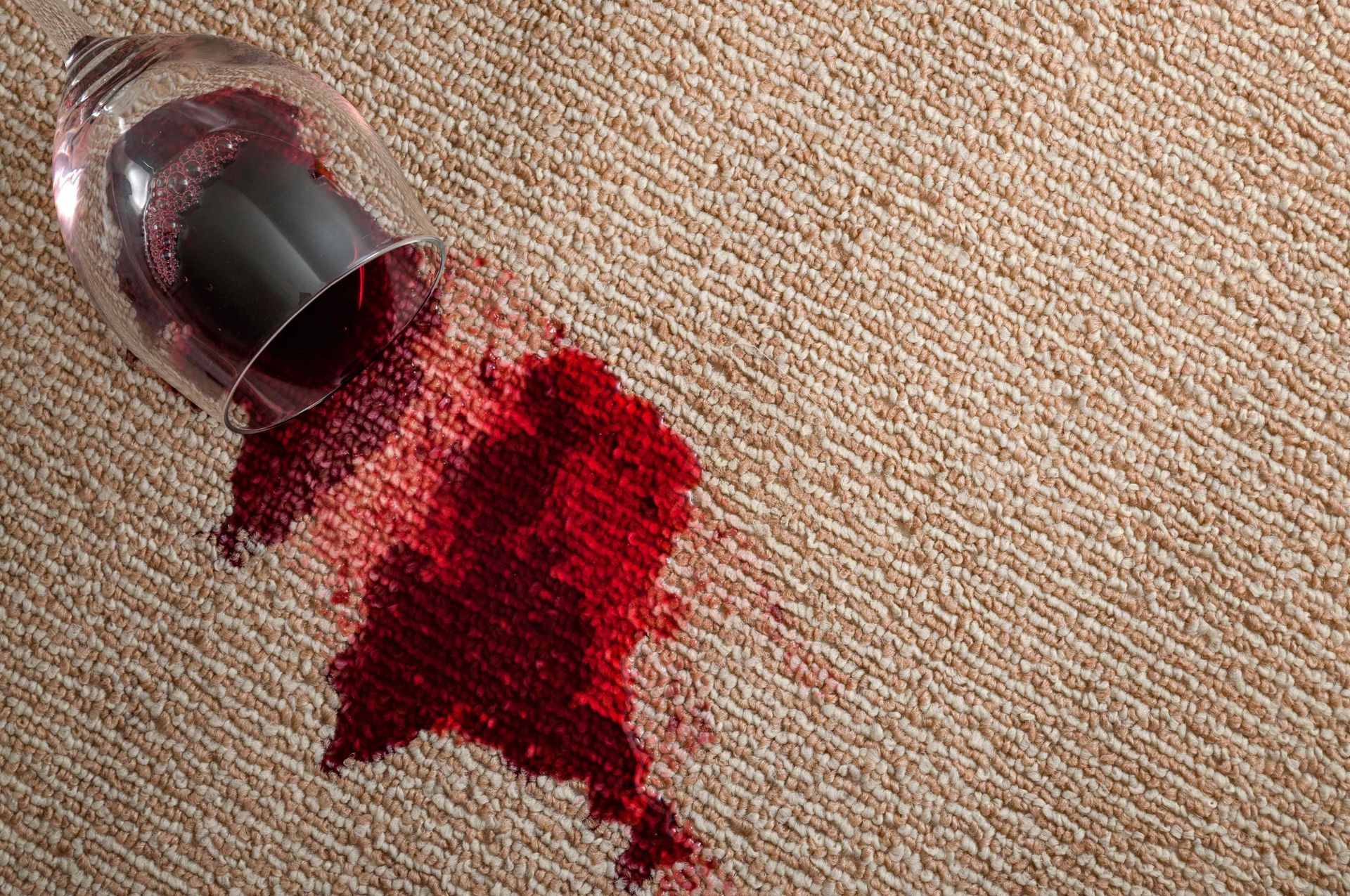 A glass of red wine spilled on a carpet