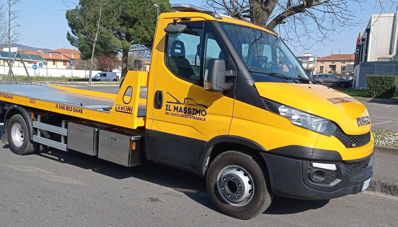 Carro attrezzi giallo parcheggiato su una strada; il pianale è visibile. Sulla fiancata è stampato