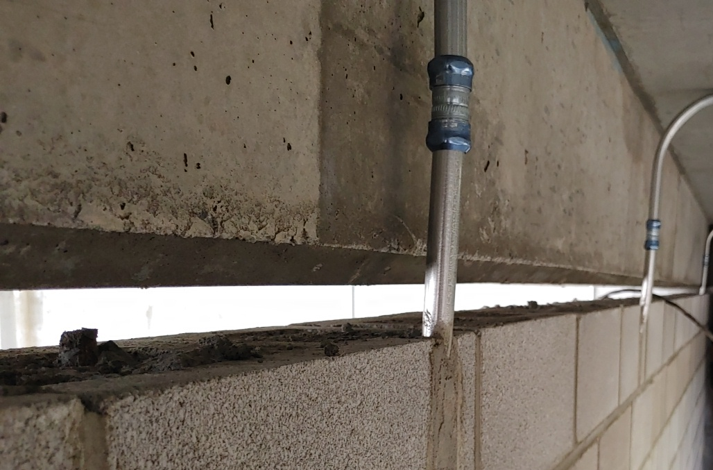 Un tuyau est suspendu au côté d'un mur de briques.