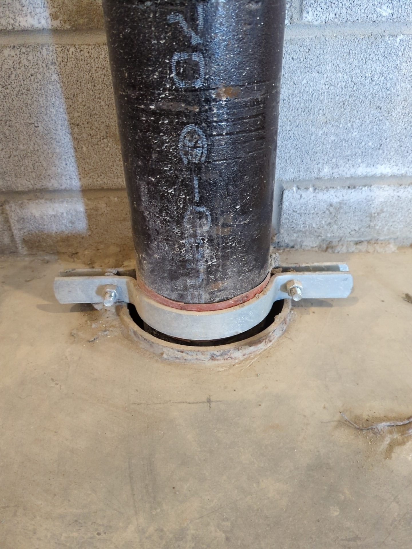Un tuyau est posé sur un sol en béton à côté d'un mur de briques.