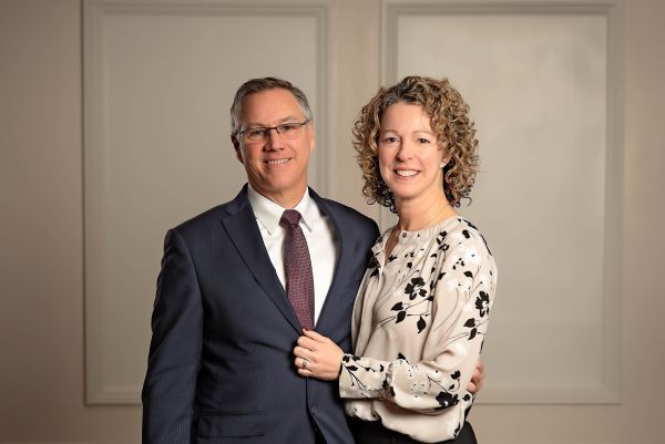 Smiling couple posing in formal attire against a neutral studio backdrop