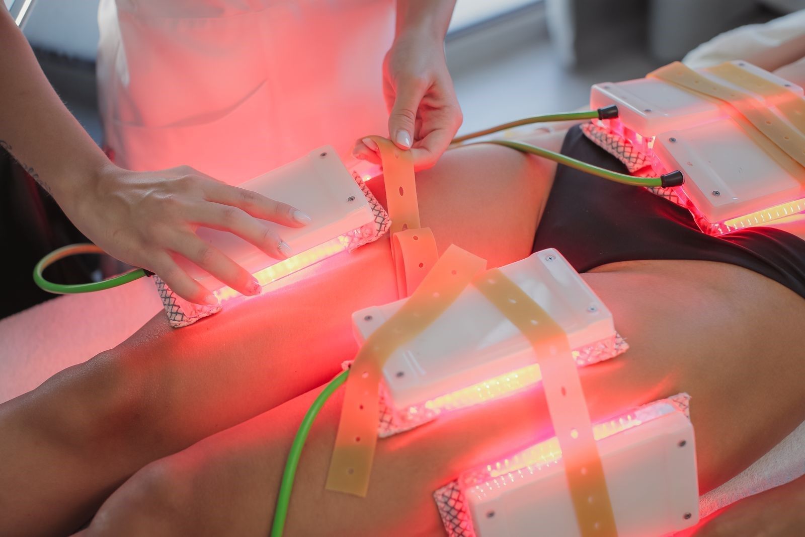 Cuscinetti per la terapia con luce rossa sulla schiena di una persona mentre le mani regolano i dispositivi