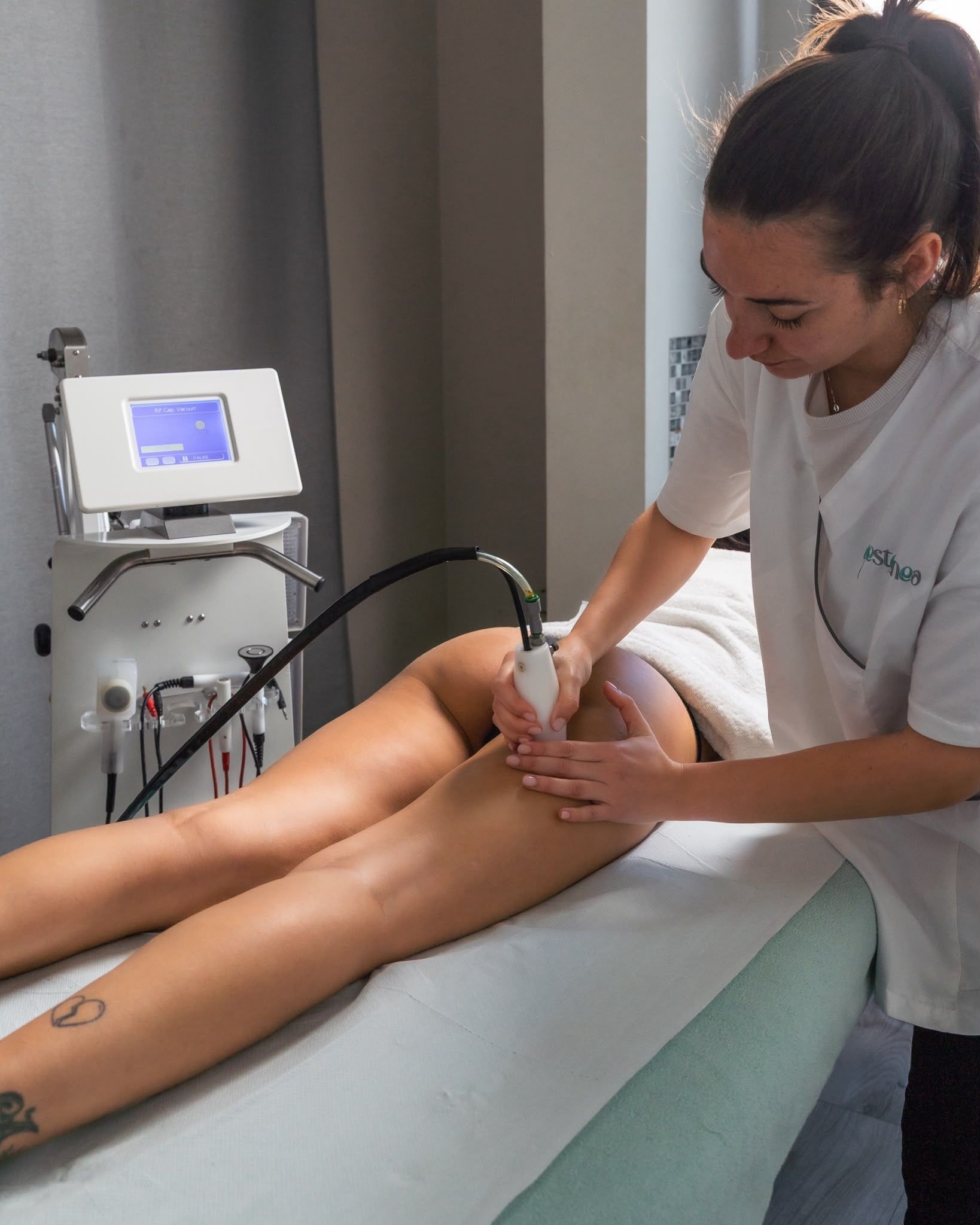 Estetista esegue un trattamento alle gambe con un dispositivo portatile in una sala spa.