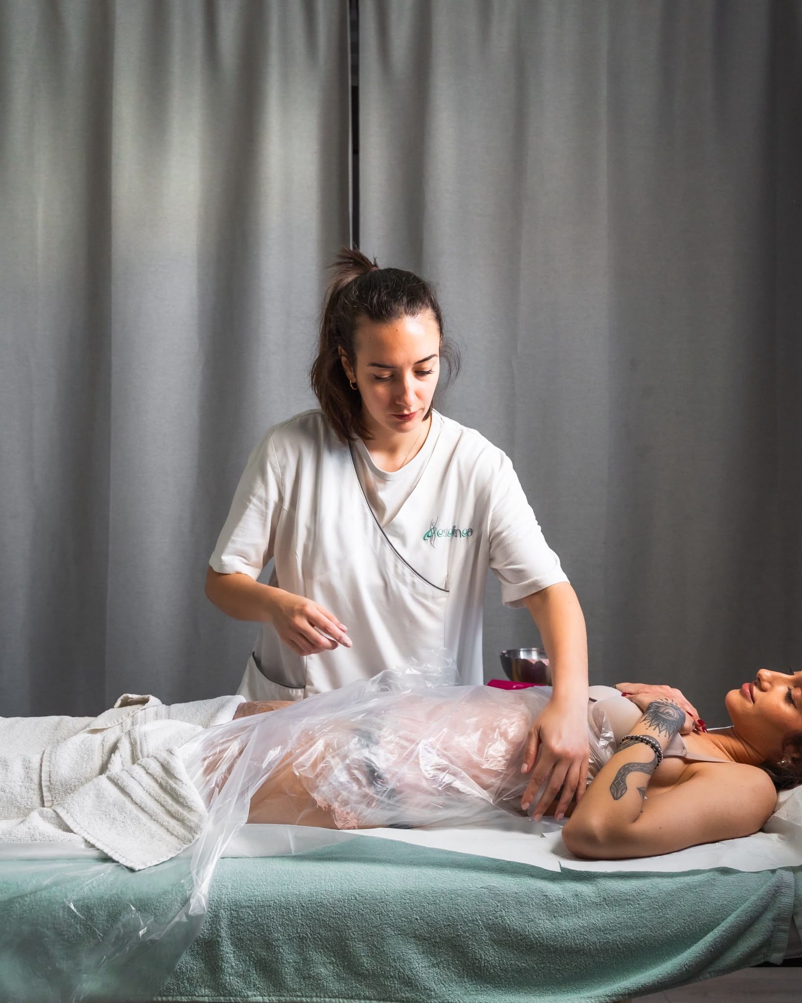 Un massaggiatore applica un impacco per il corpo a un cliente sdraiato su un lettino da trattamento in una sala spa.