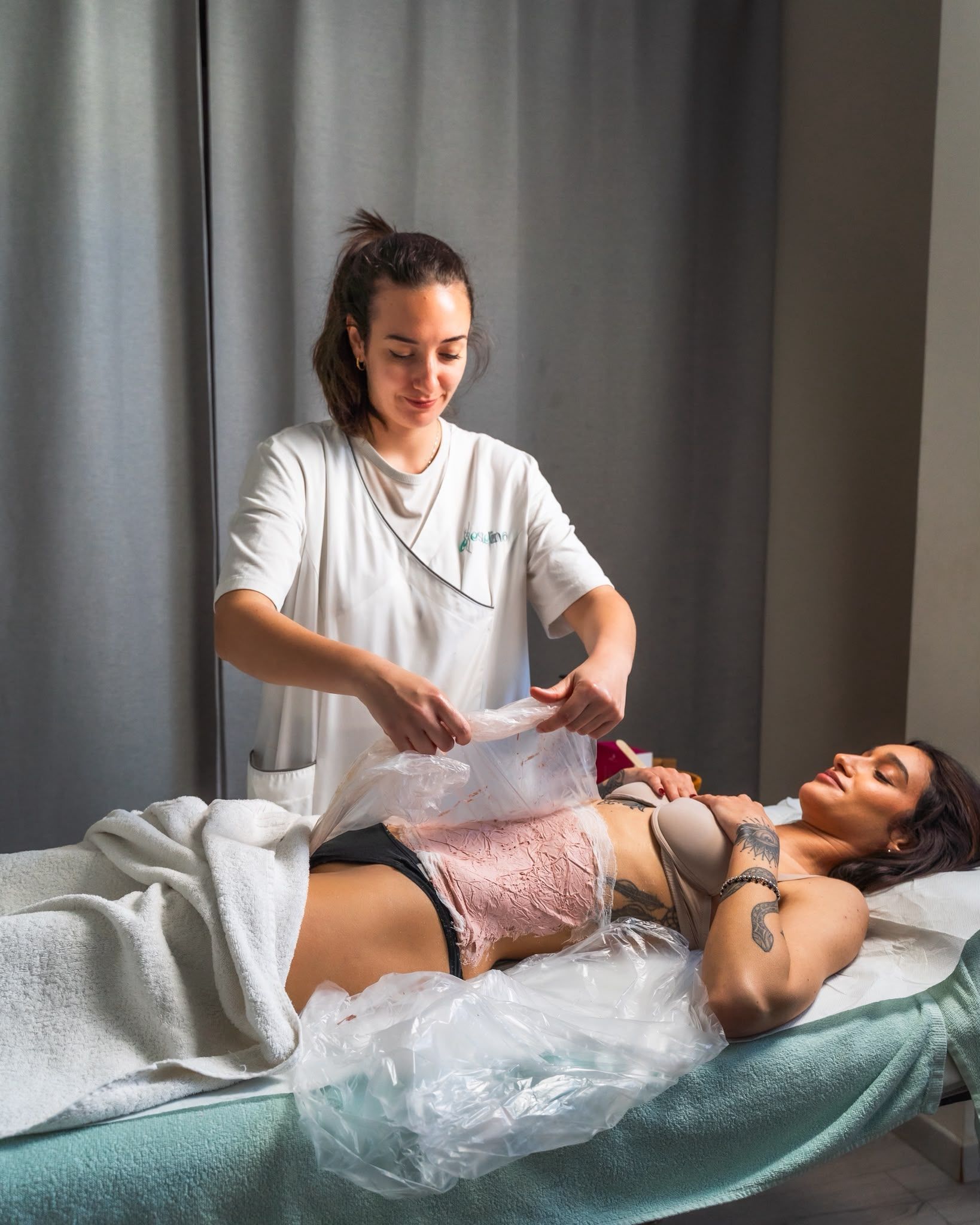 Una donna esegue un trattamento di epilazione con cera su una cliente sdraiata su un lettino.