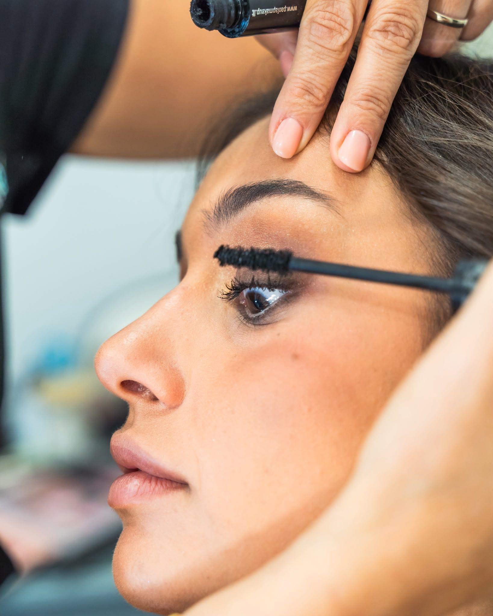 Truccatrice che applica il mascara agli occhi di una donna durante un trattamento di bellezza.