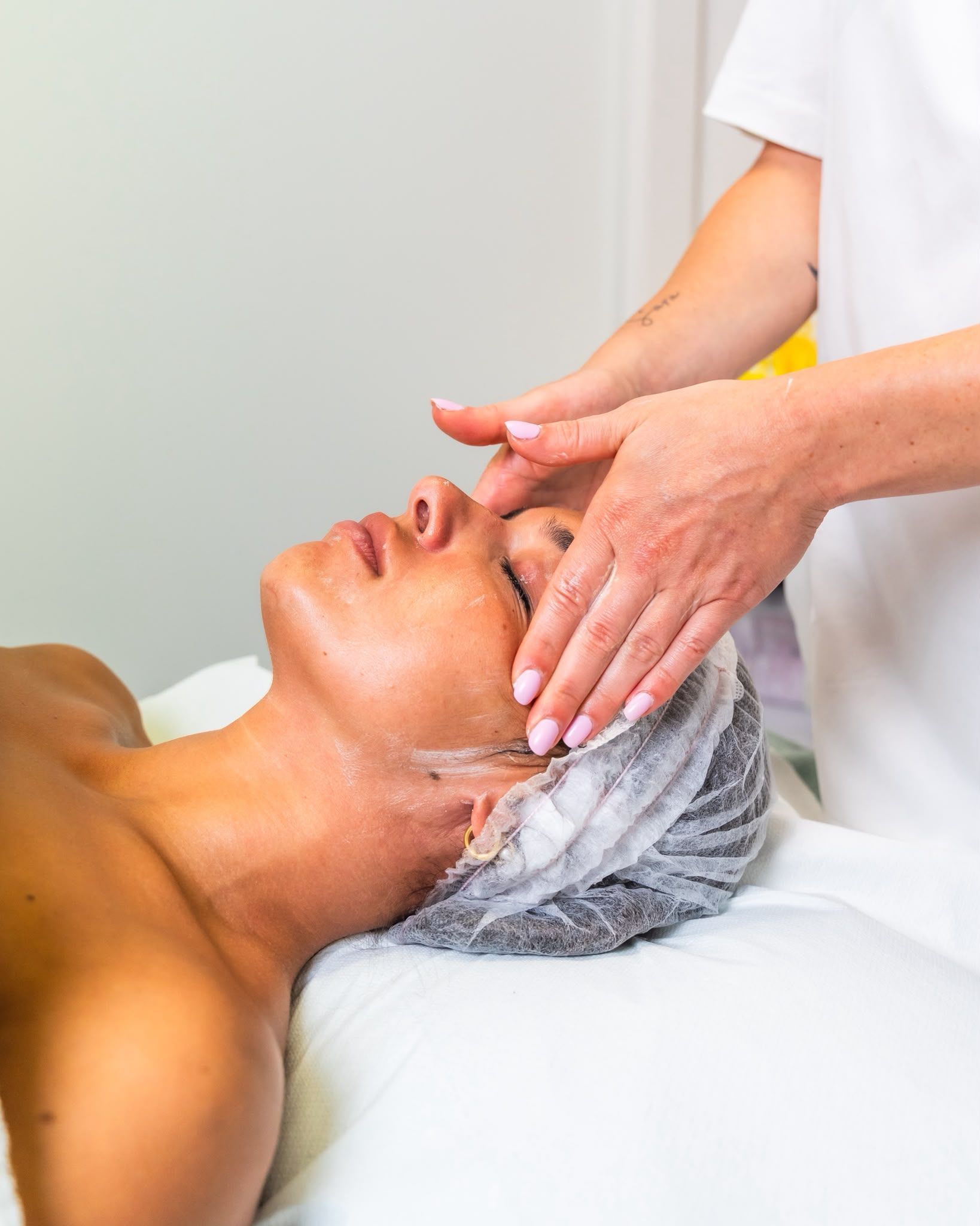 Massaggio facciale con detergente schiumogeno applicato a un cliente sdraiato in un ambiente spa.