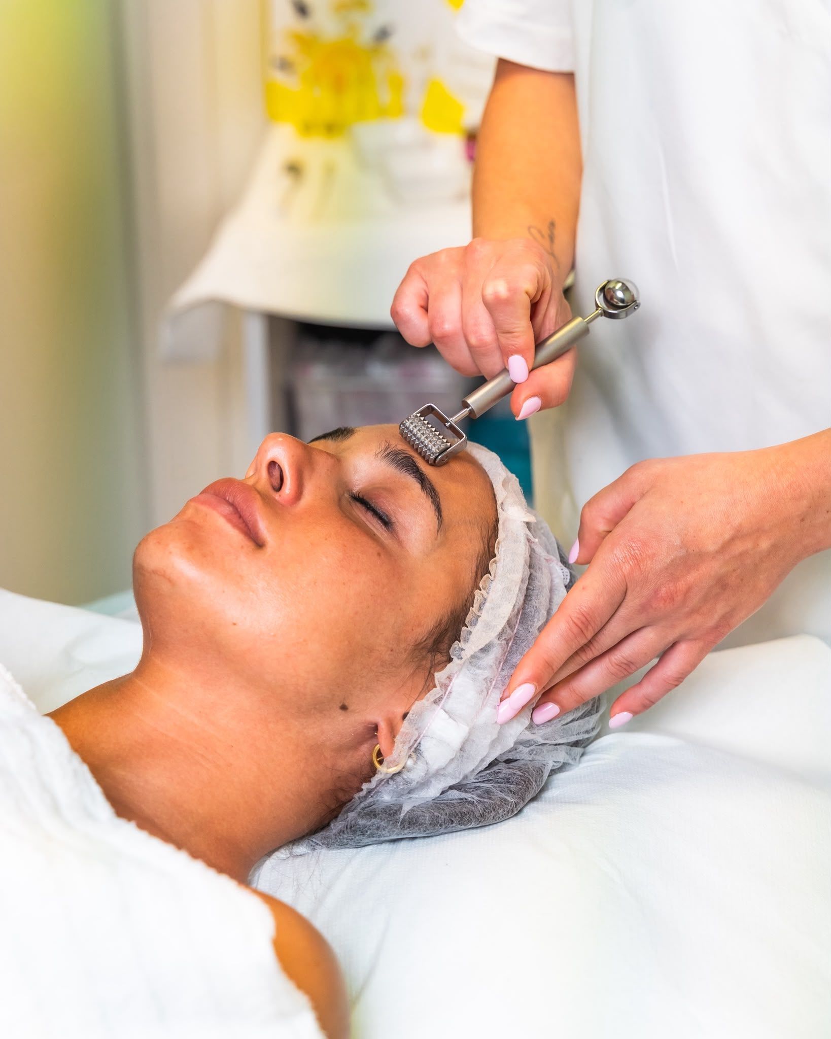 Trattamento viso in una spa con spazzola detergente sul viso di una cliente in una cabina per trattamenti.