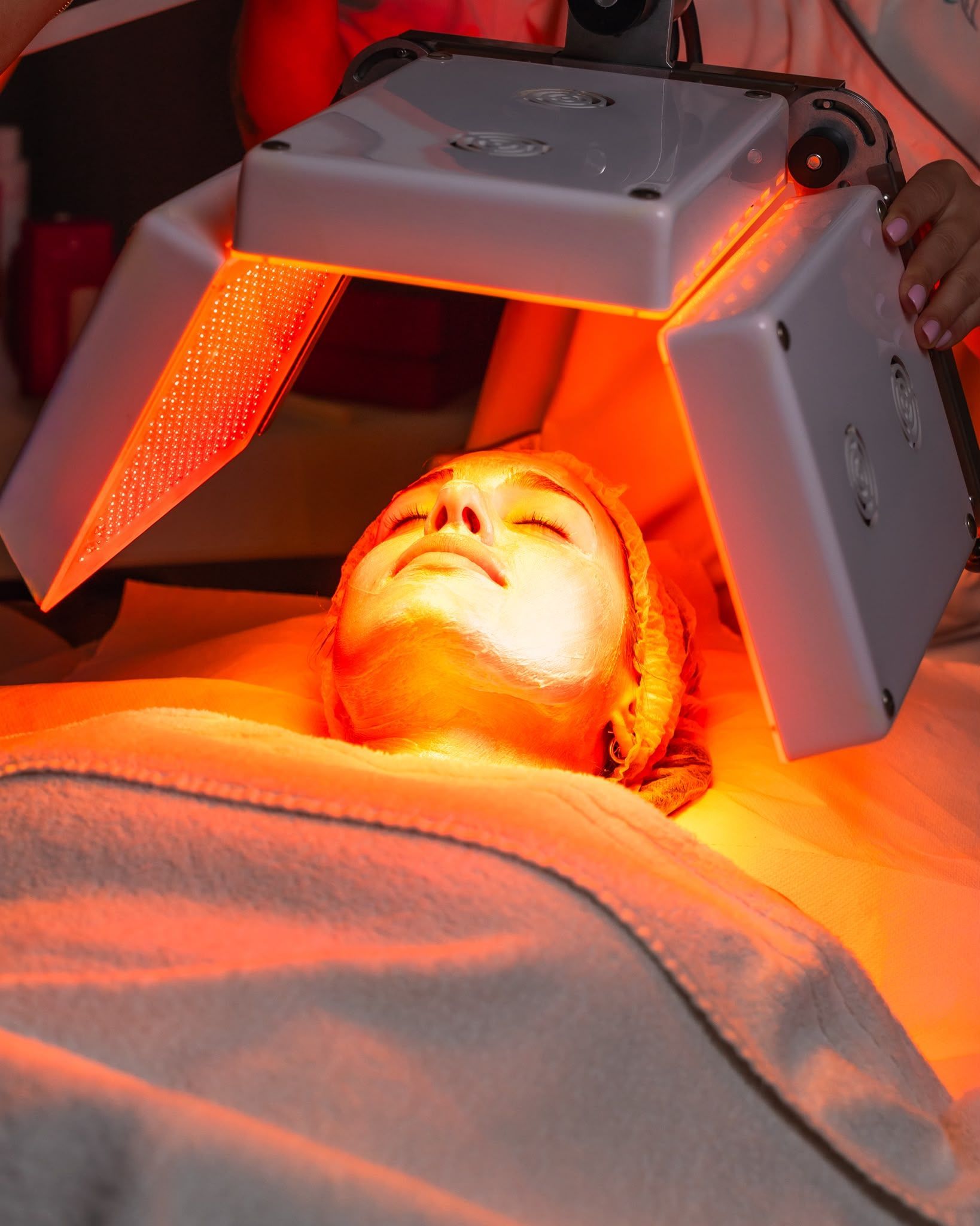 Persona sdraiata su un lettino da trattamento sotto un dispositivo per la terapia a luce rossa.