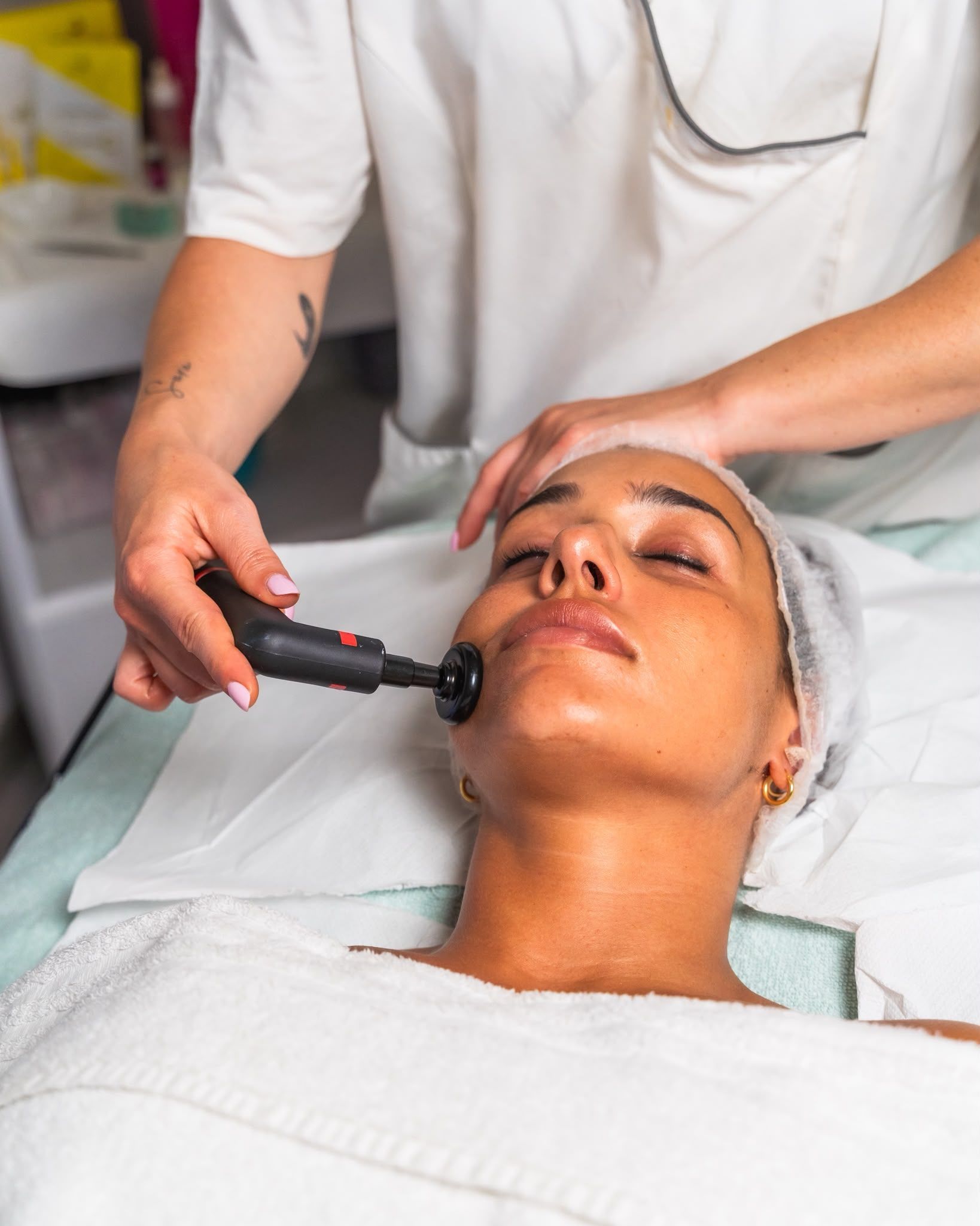 Trattamento viso con dispositivo portatile applicato al viso del cliente in un ambiente spa.