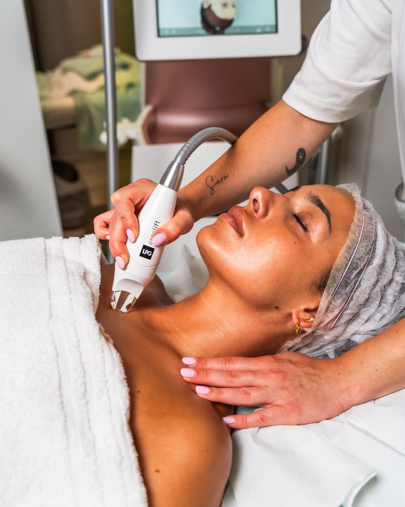 Trattamento viso in una spa, con un'estetista che utilizza un dispositivo portatile su una cliente sdraiata.
