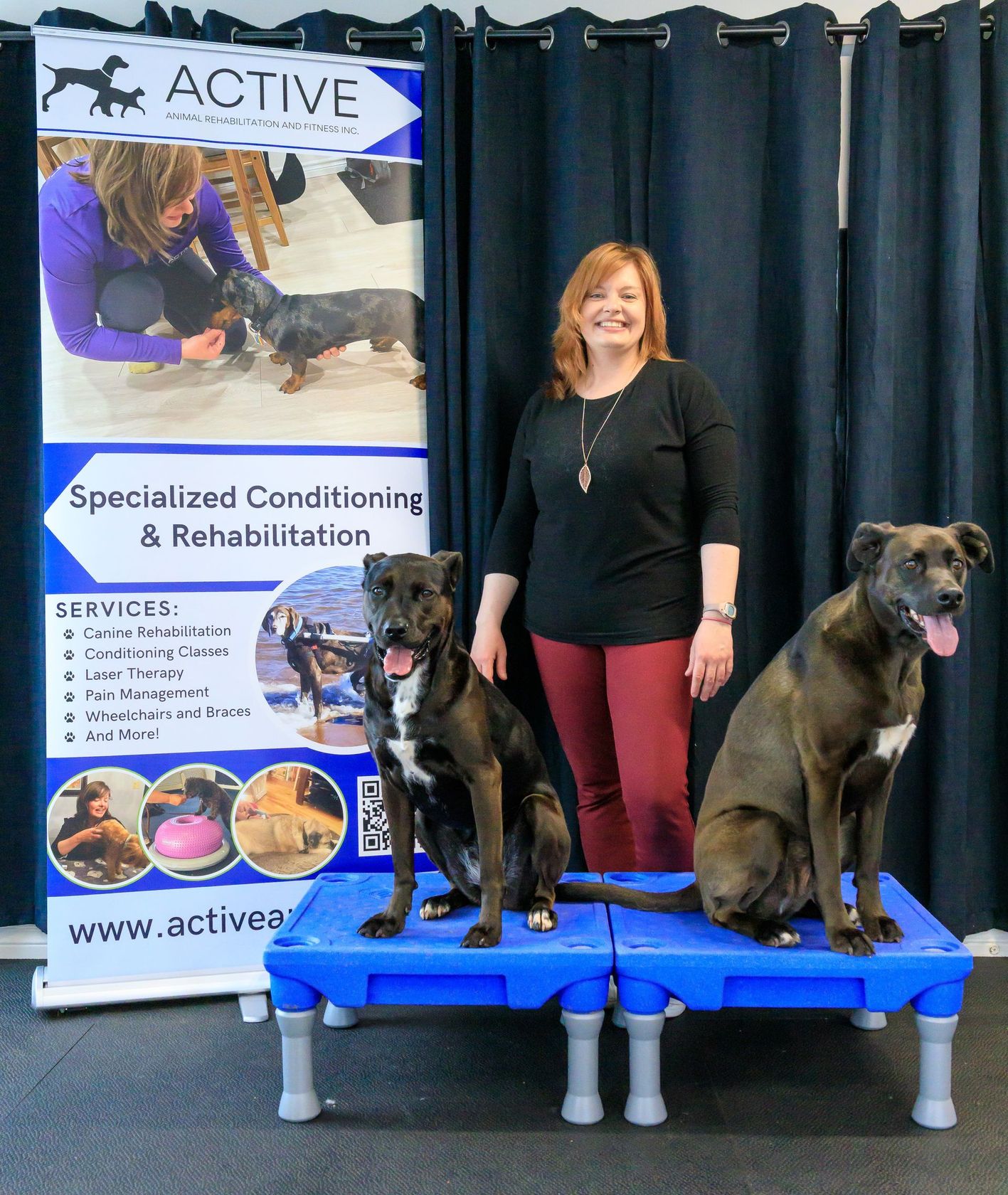 Woman with two dogs on blue platforms beside an Active Specialized Conditioning & Rehabilitation banner