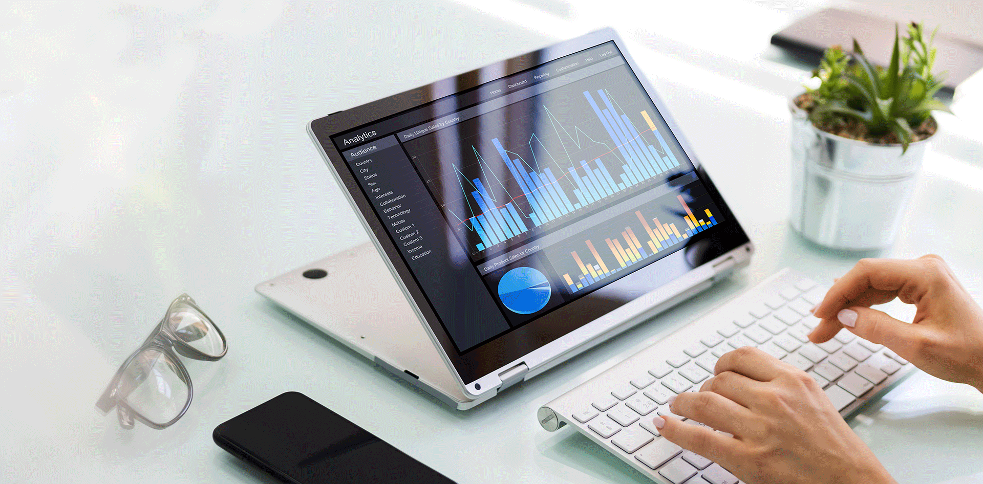 A person is typing on a laptop computer with a graph on the screen.