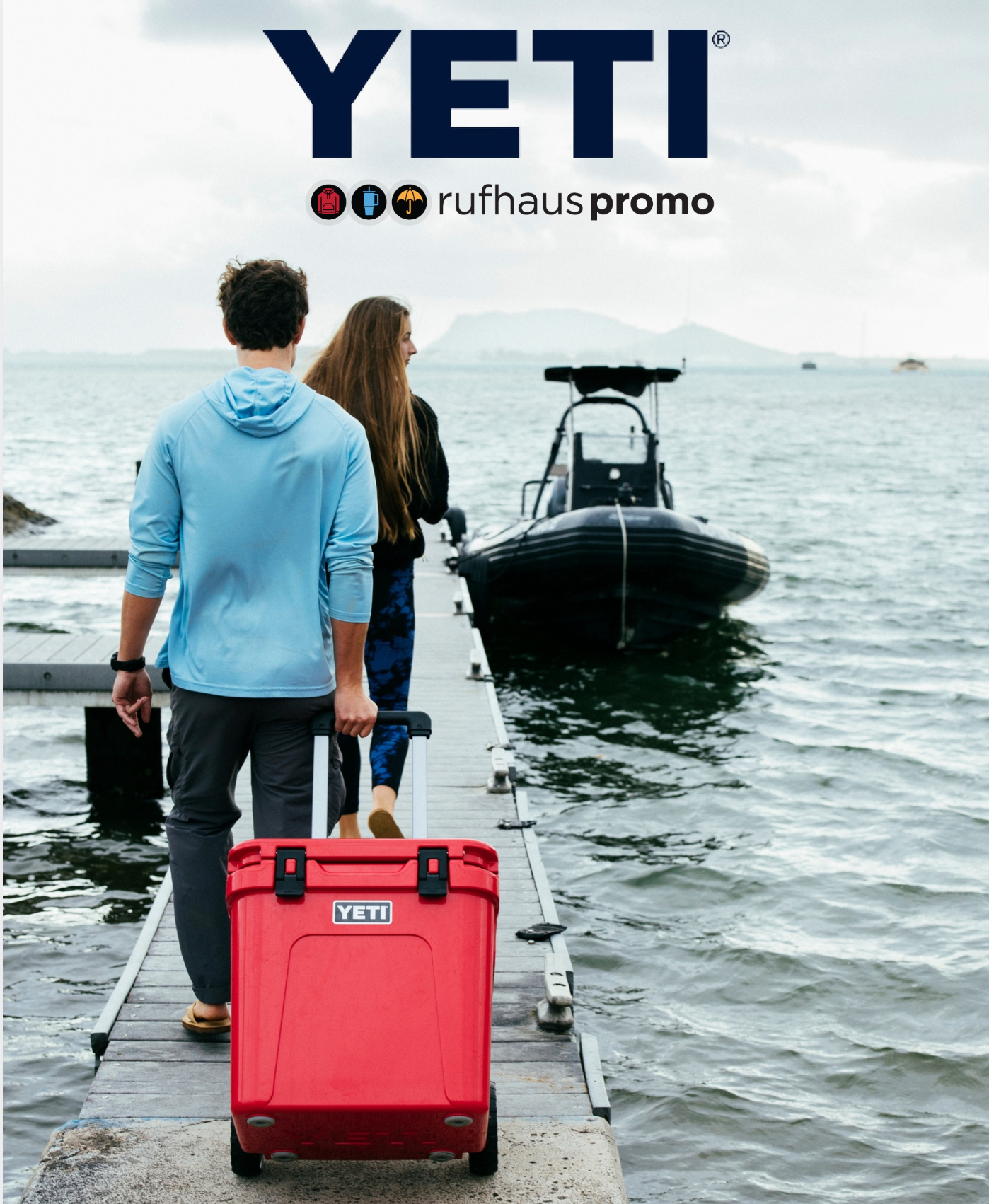 Two travelers with a red YETI cooler walk down a dock toward a black boat on calm water on the catalog