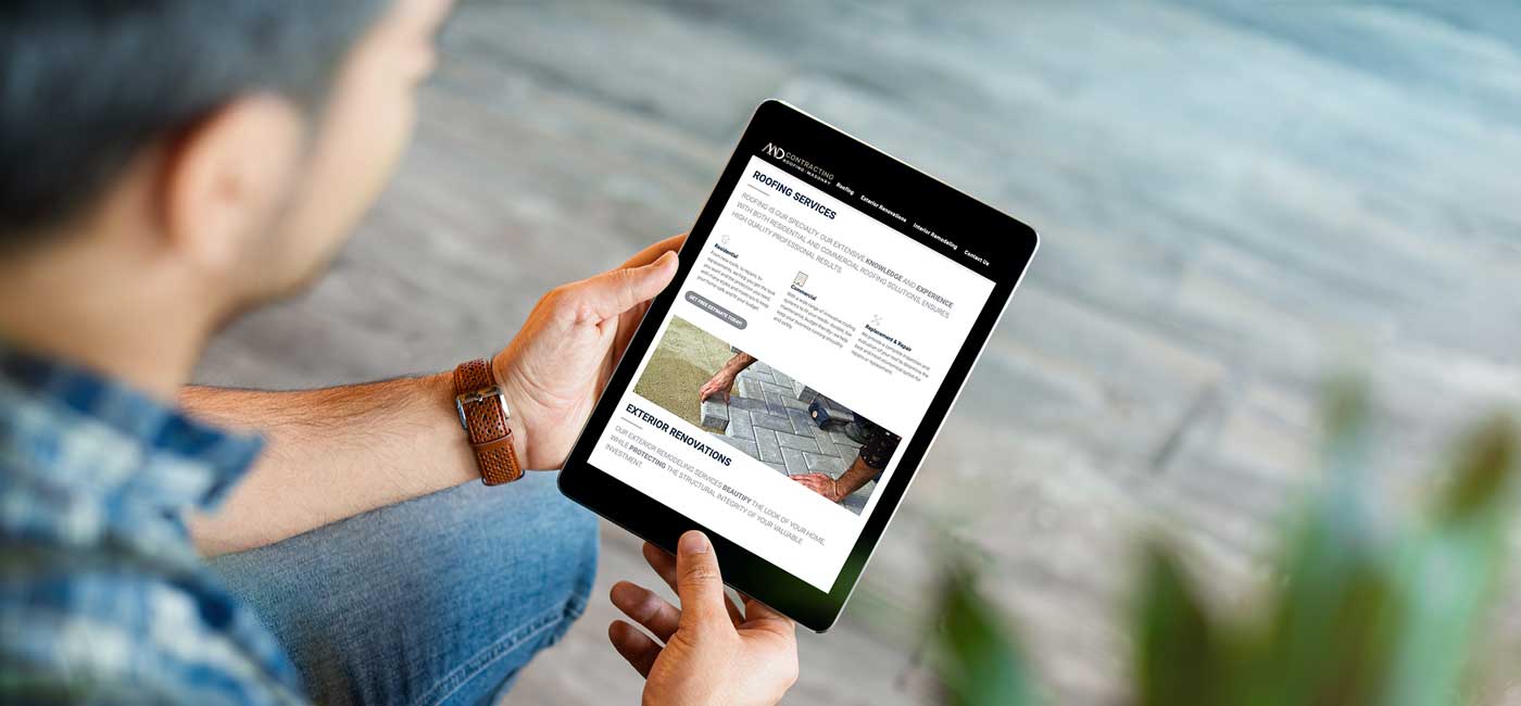 A man is sitting on the ground using a tablet computer viewing MD contracting