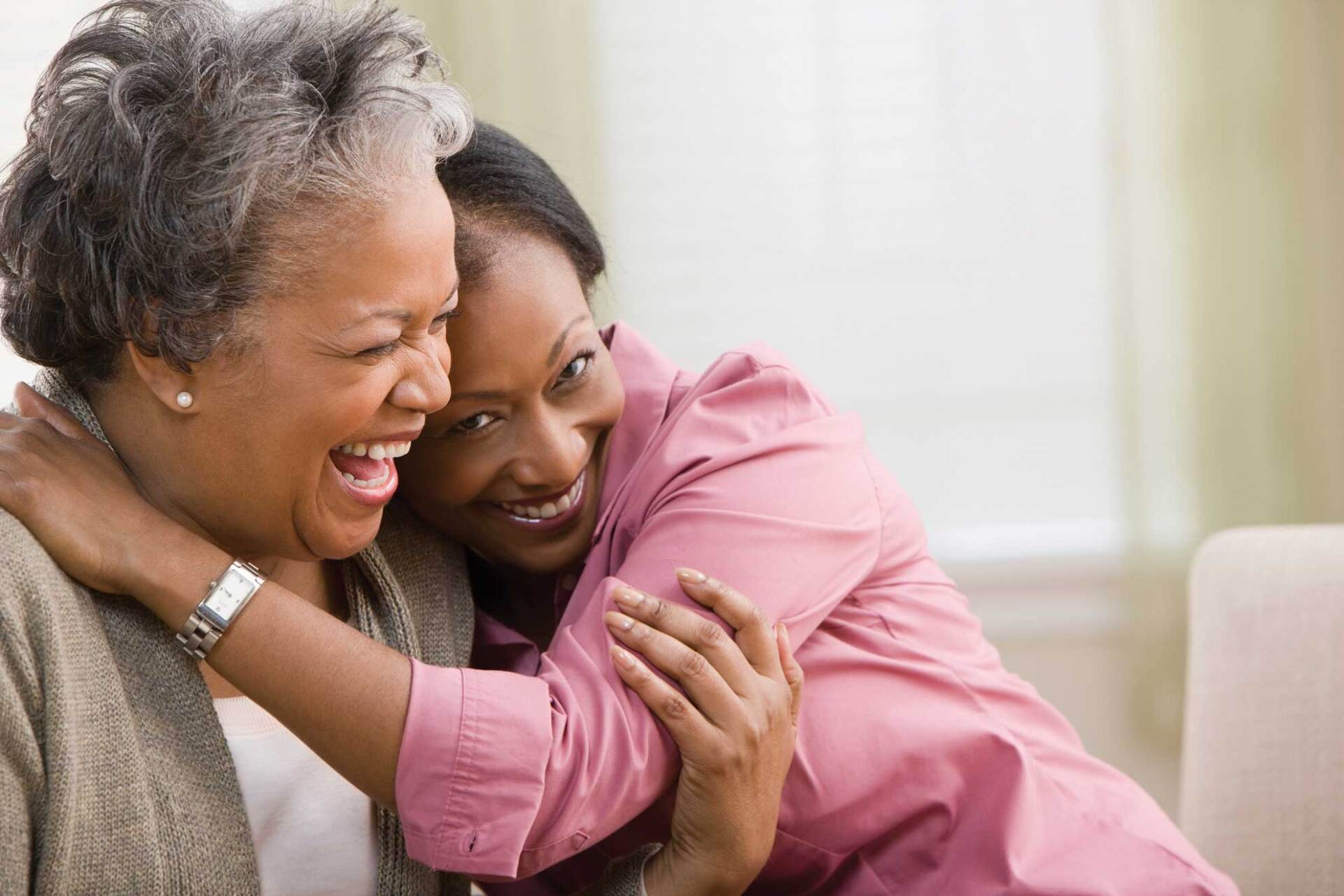 A young woman is hugging an older woman on a couch.