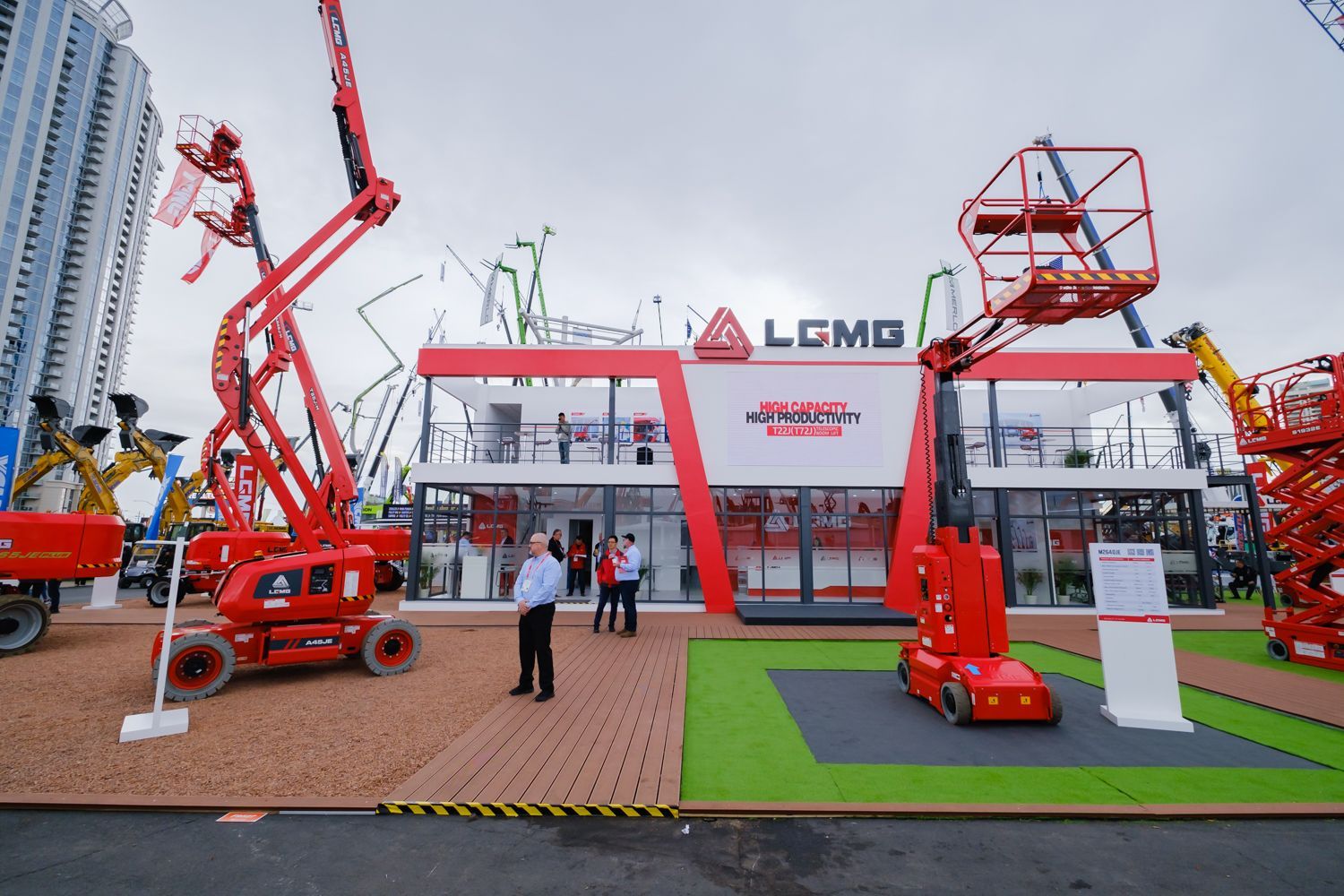 Construction equipment display booth with red machinery, LCMG sign, and people.