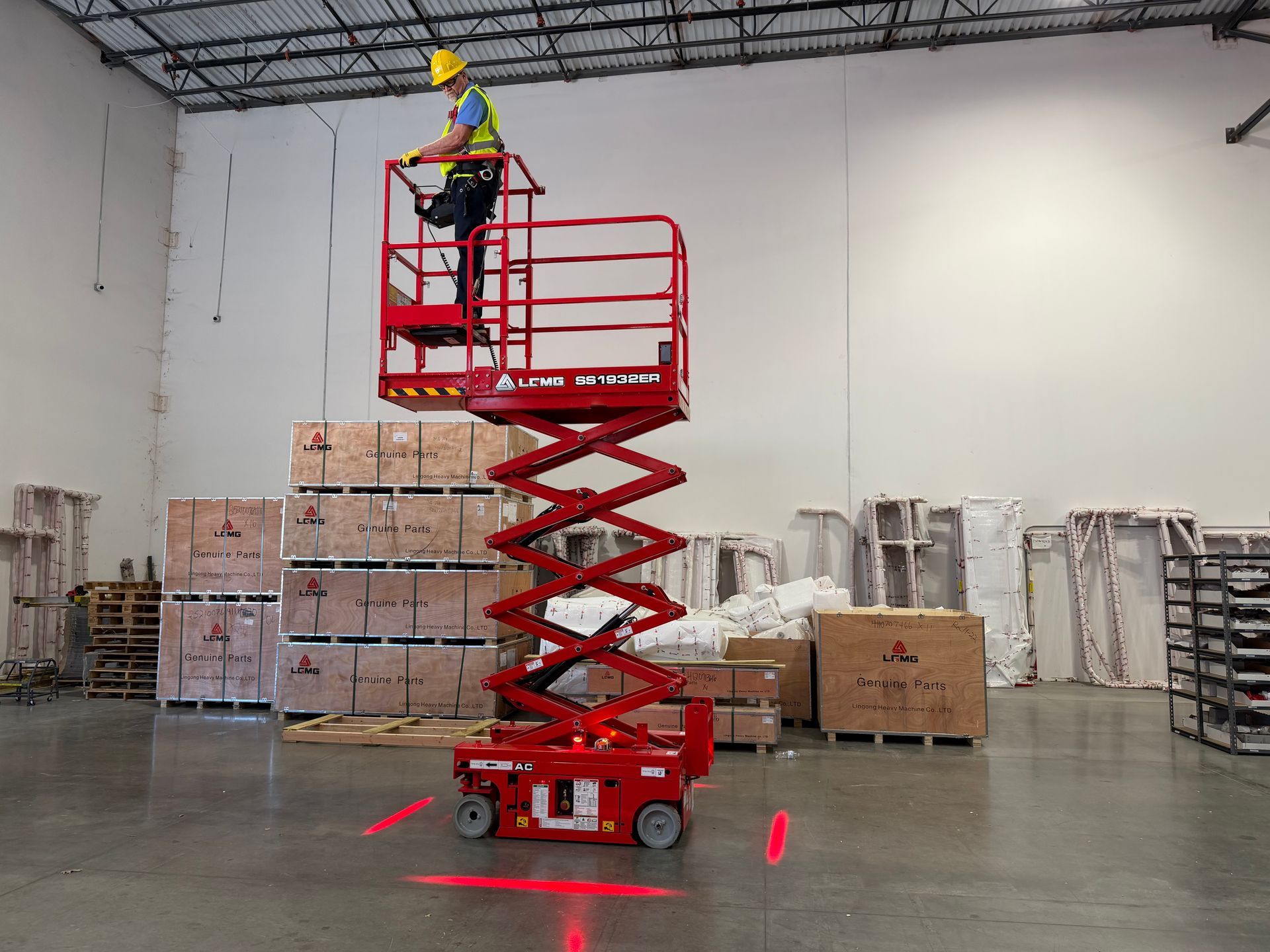 Red electric micro scissor lift with perimiter lighting and step deck with construction worker