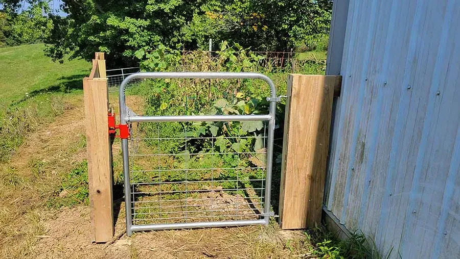 A metal gate is sitting next to a wooden post.