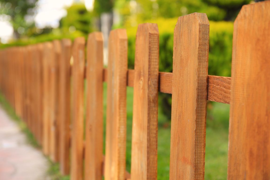 A close up of a wooden picket fence in a park.