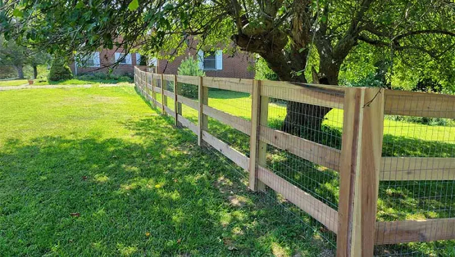 A wooden fence surrounds a lush green field.