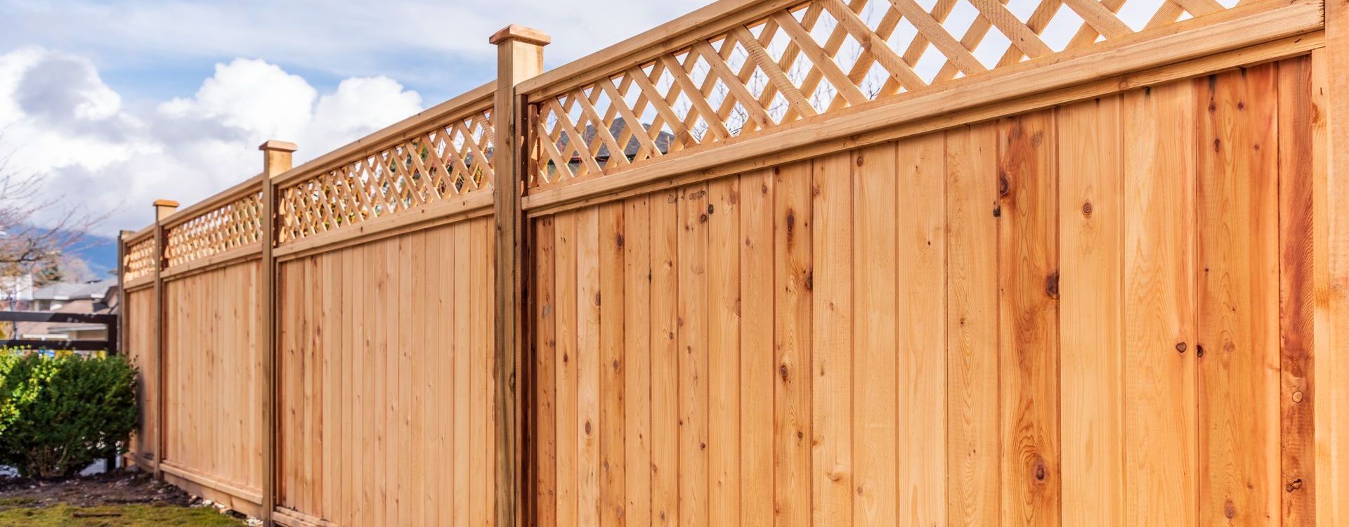 A wooden fence with a lattice top is in a backyard.