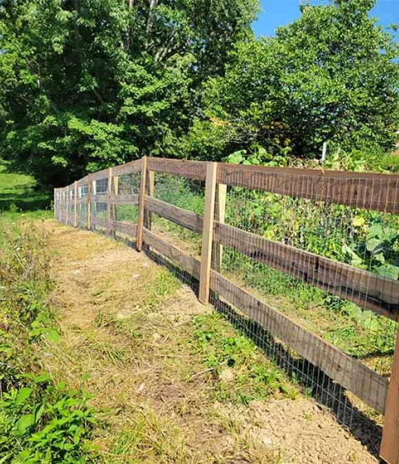 A wooden fence with a wire fence in the middle of a field.