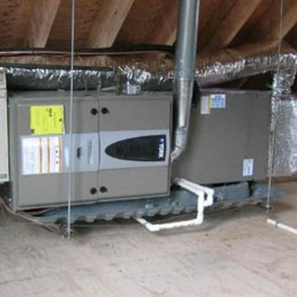 Attic HVAC units with exposed ductwork and white condensate pipes on the floor