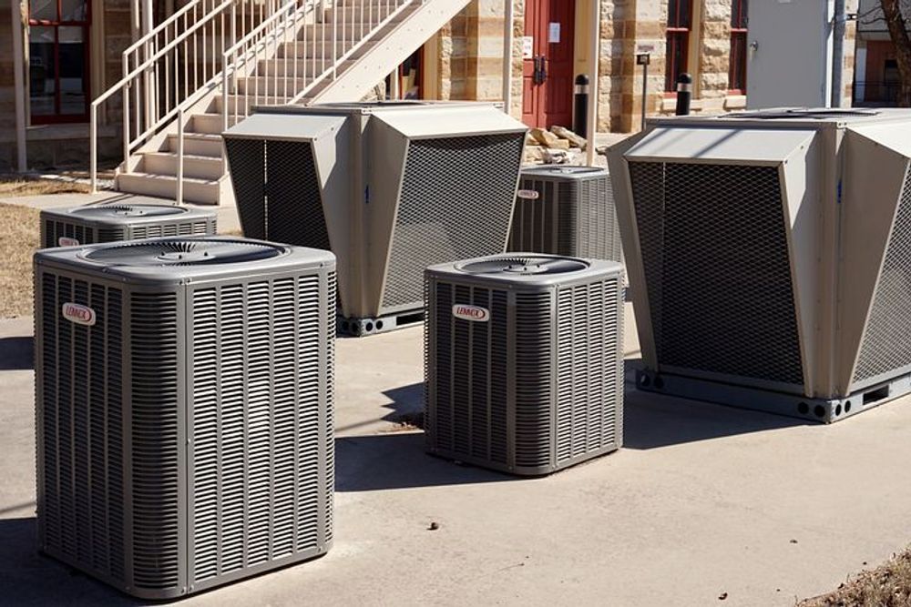 Outdoor row of large gray HVAC units on a concrete surface beside a building.