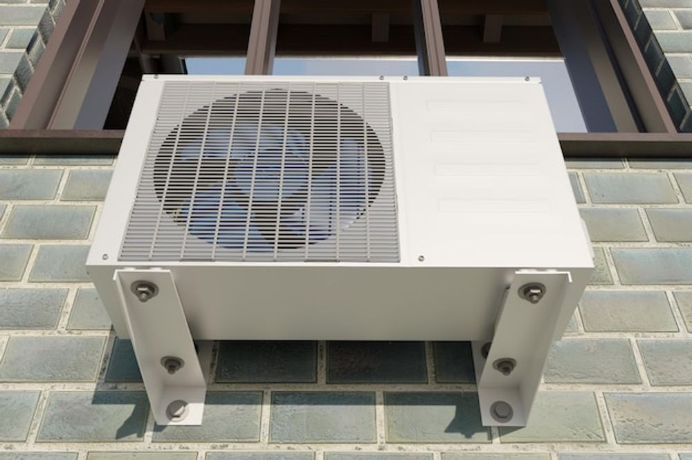 Wall-mounted outdoor air conditioner unit on a brick building facade