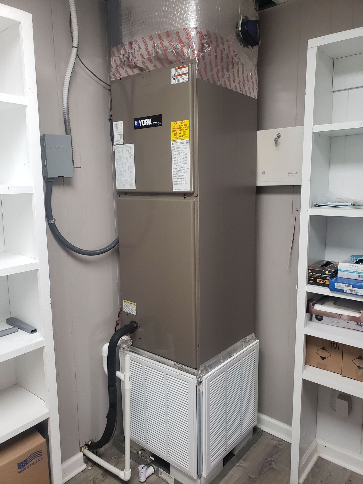 HVAC unit and ductwork in a utility closet with shelving and storage bins