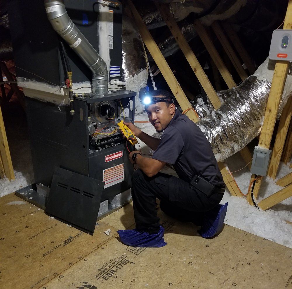 Hands in blue nitrile gloves holding a chrome P-trap pipe beneath a white bathroom sink.