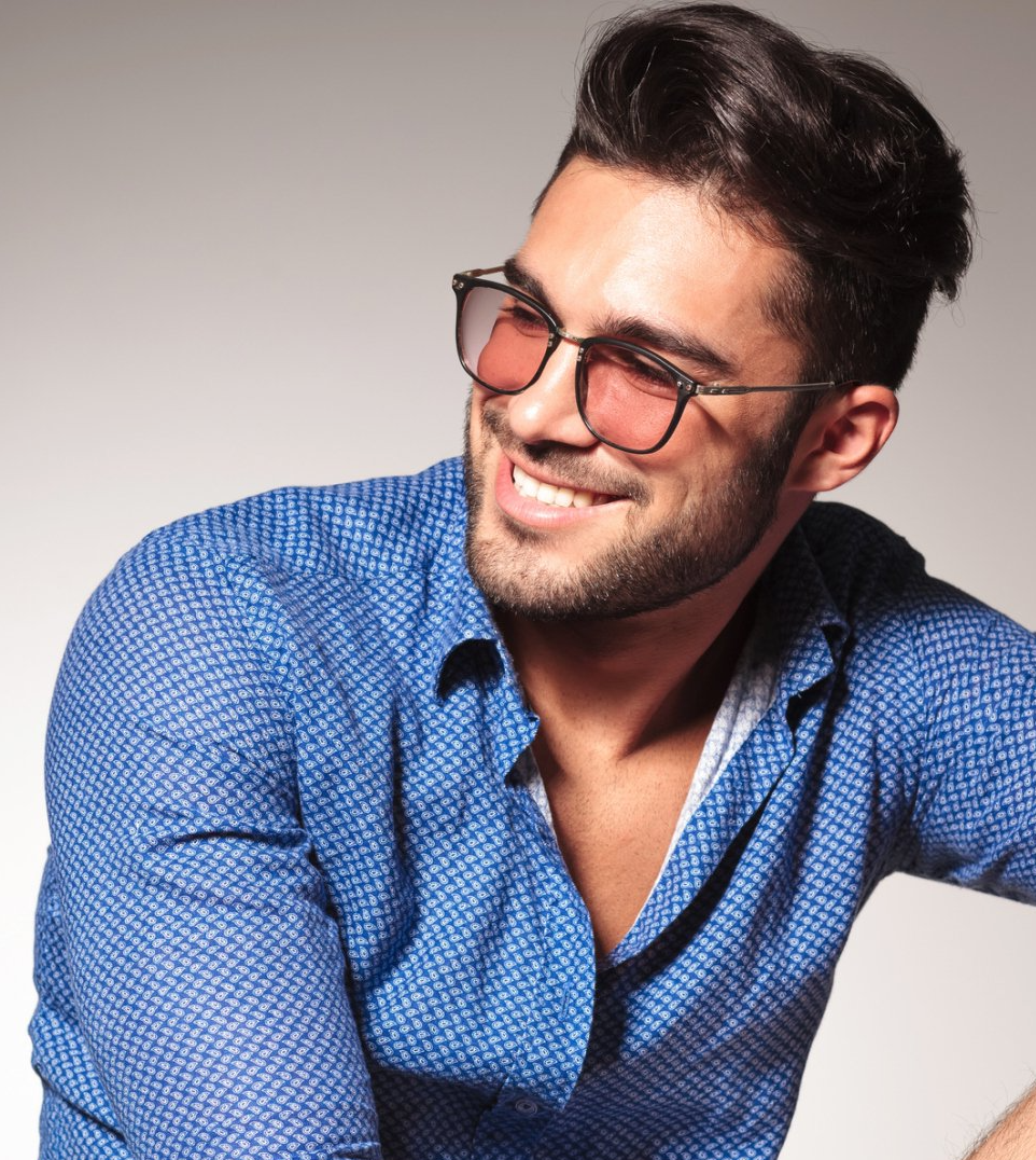 A man wearing sunglasses and a blue shirt is smiling