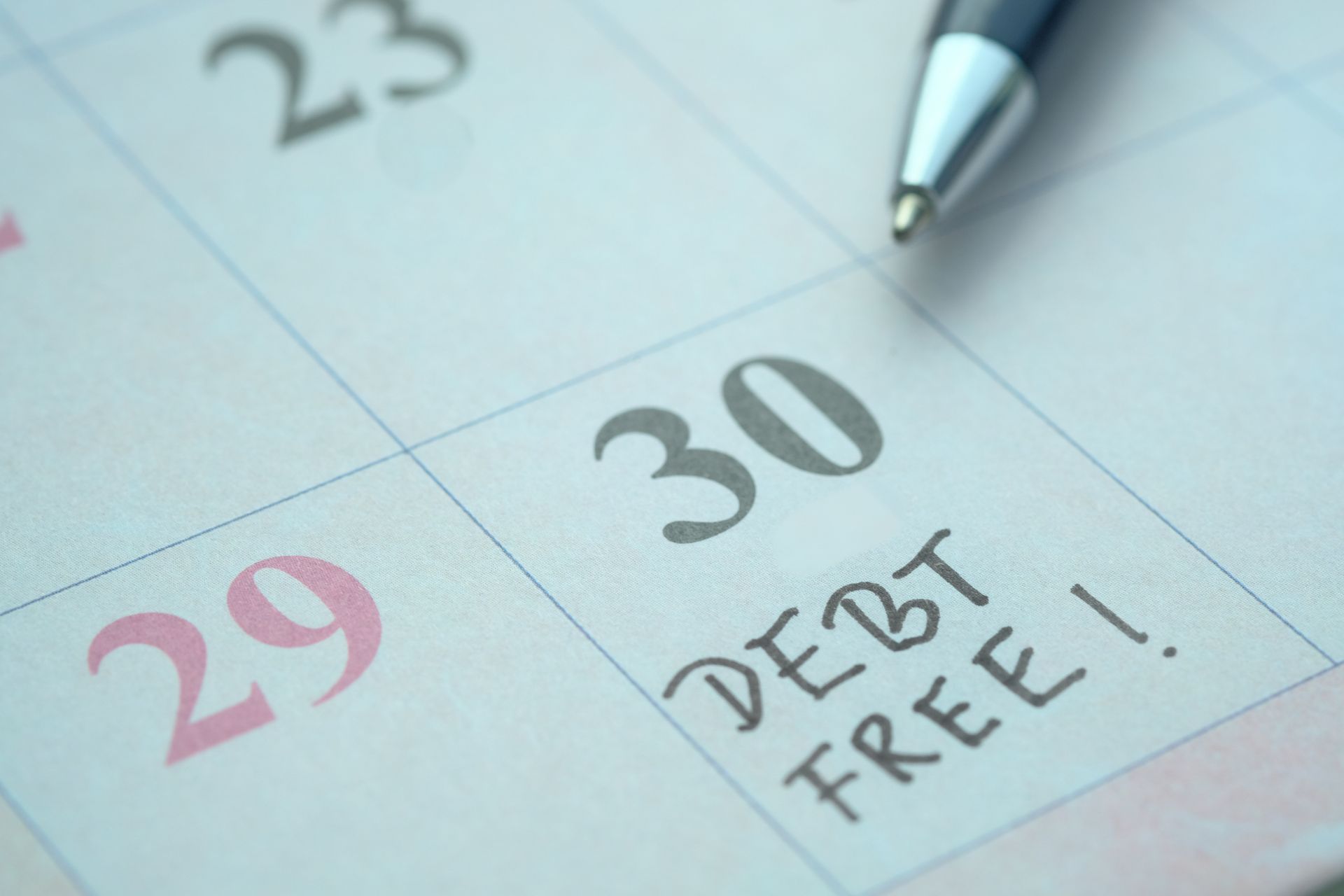 Calendar marking December 30th as 'DEBT FREE' day with pen, representing student loan relief success