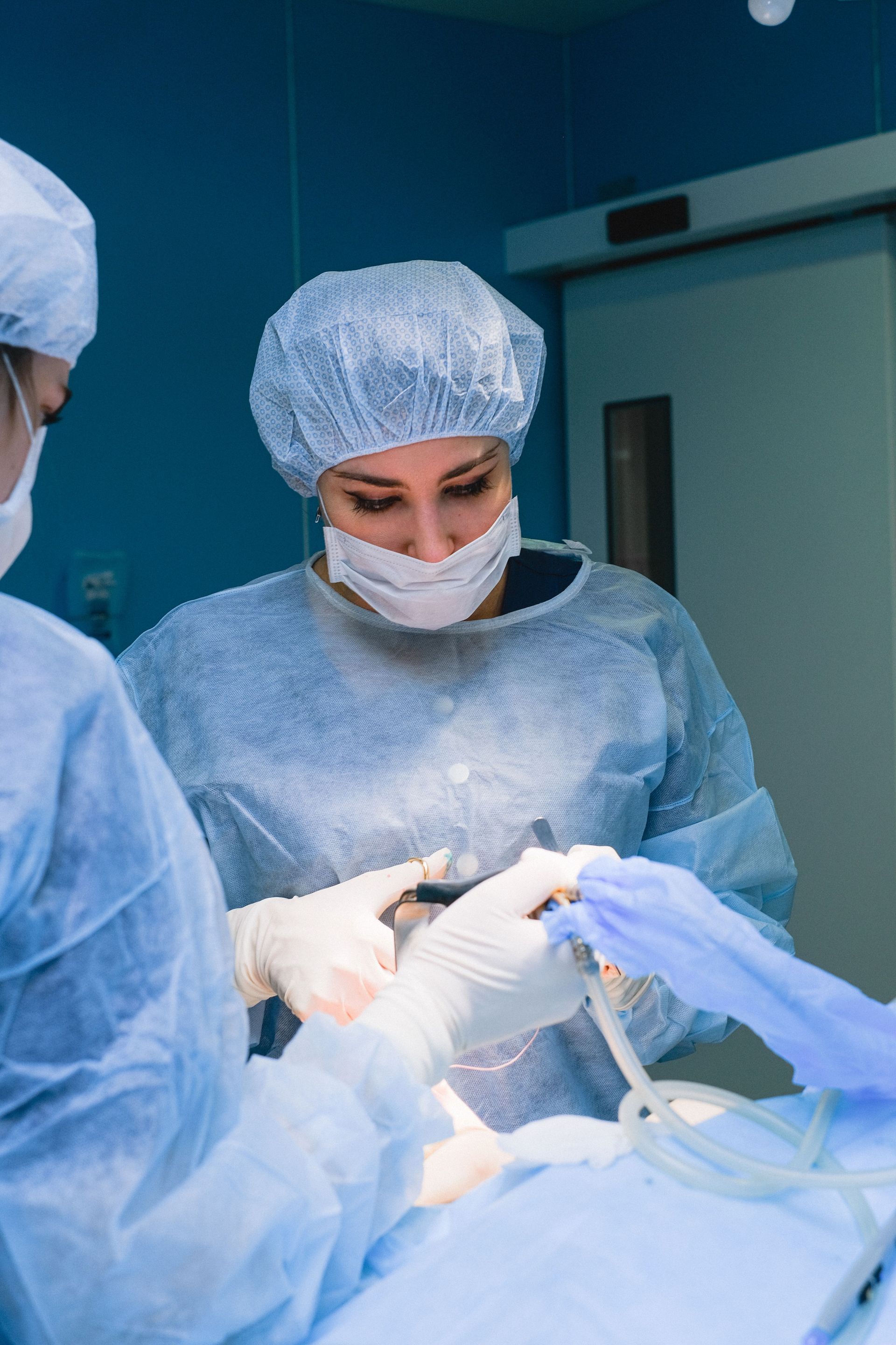 Surgeons in blue scrubs performing an operation in an operating room