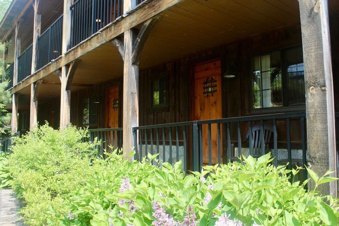 A row of wooden houses with porches and flowers in front of them.