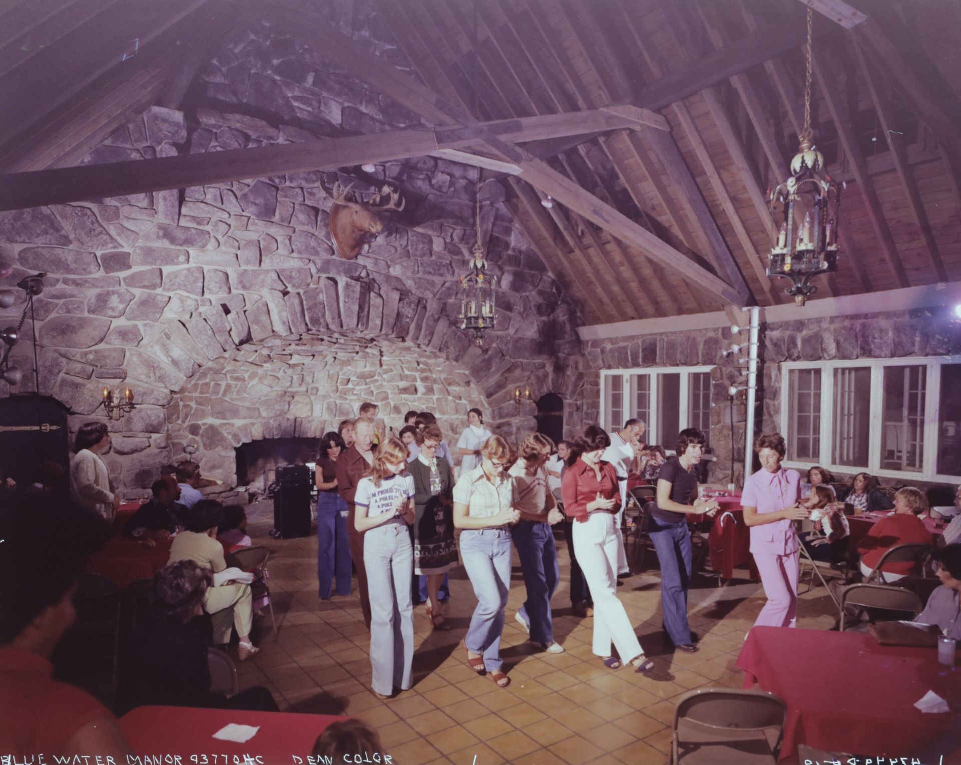 A group of people are dancing in a large room back in the day.