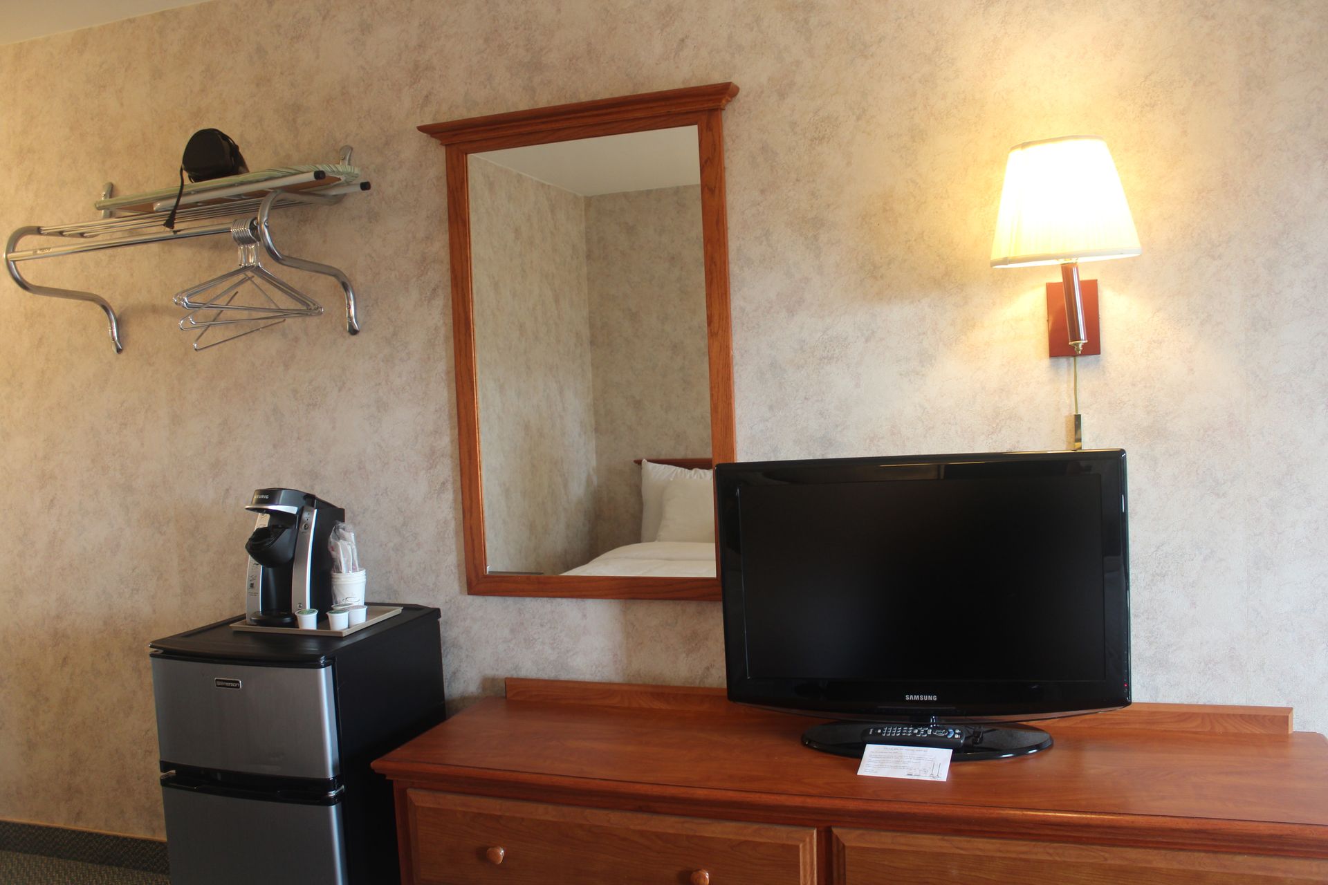 A hotel room with a flat screen tv and a refrigerator