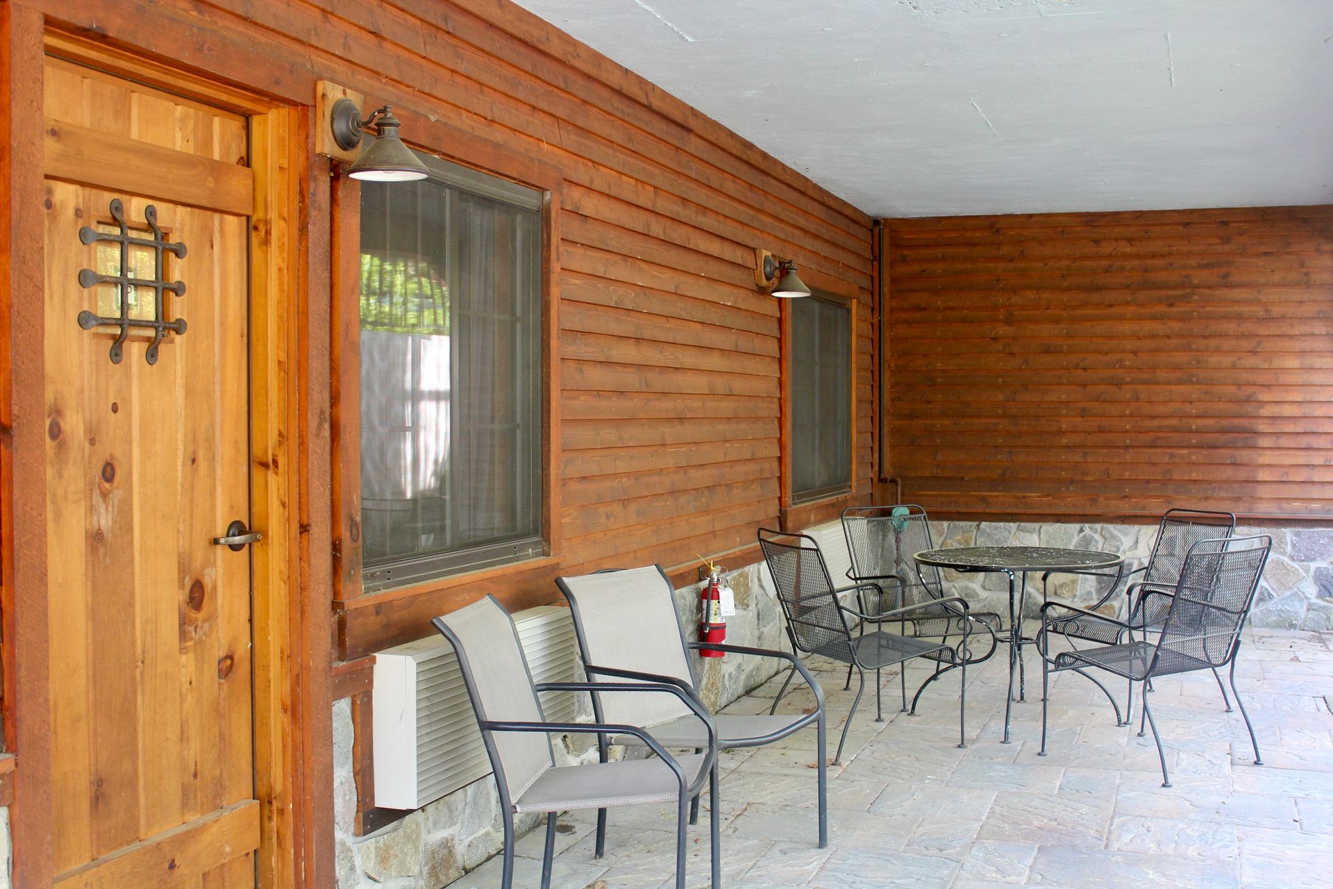 A wooden porch with chairs and tables and a fire extinguisher