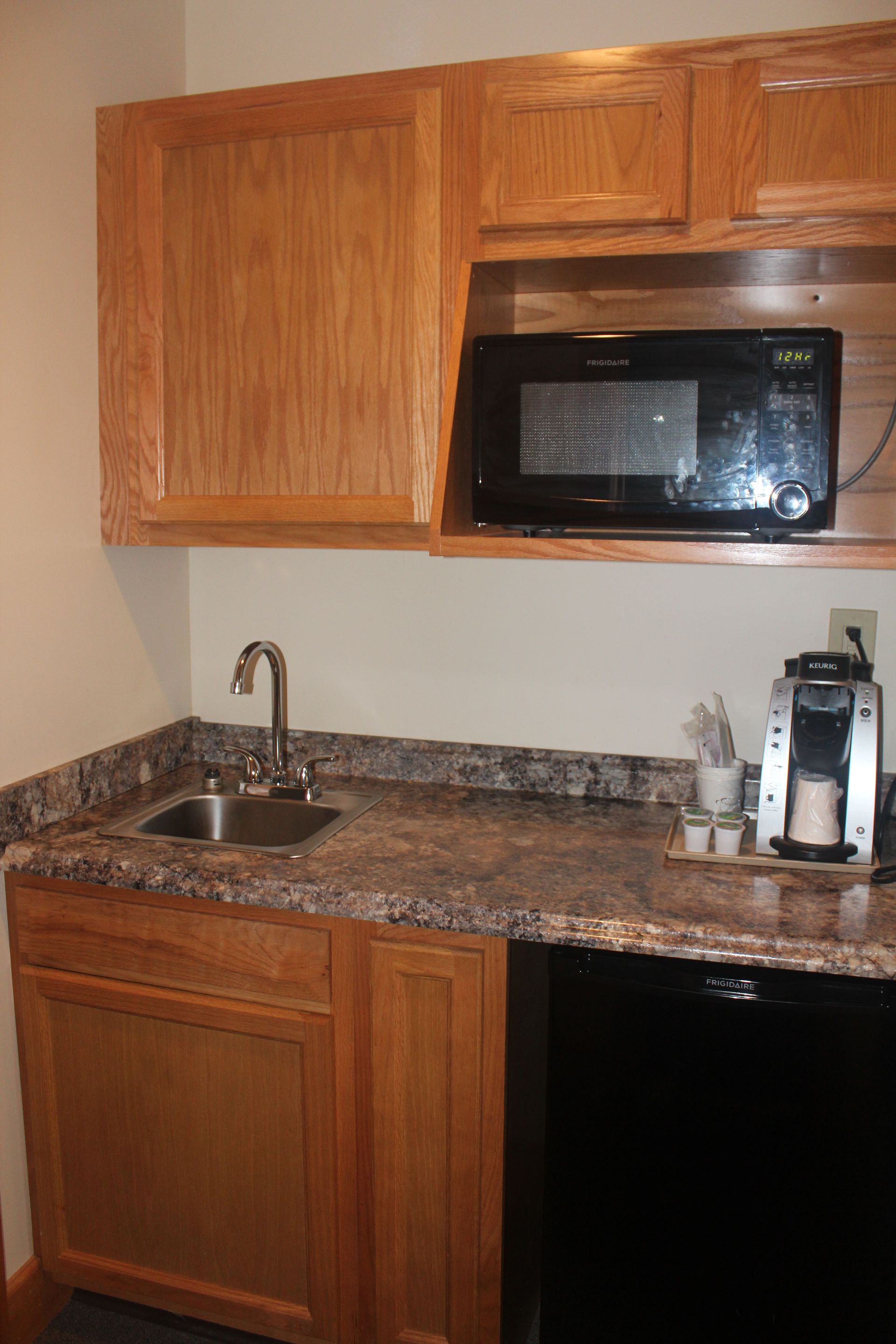 A kitchen with a sink , microwave , and coffee maker.