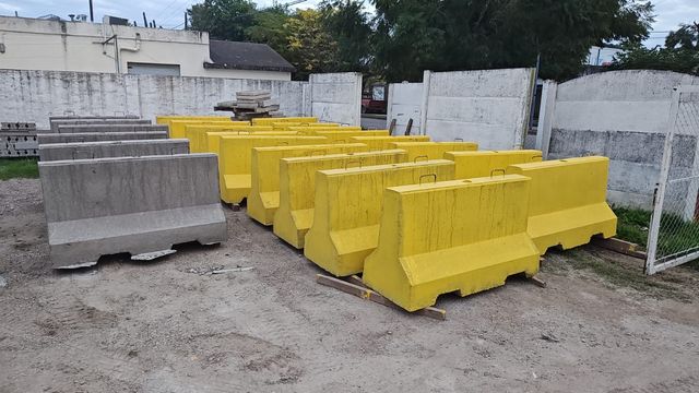 Barreras de hormigón amarillas y grises apiladas al aire libre en un patio