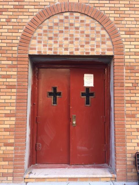 Old red painted steel church double doors with cross-shaped glass lites at 1788 Townsend Ave in the Bronx before replacement