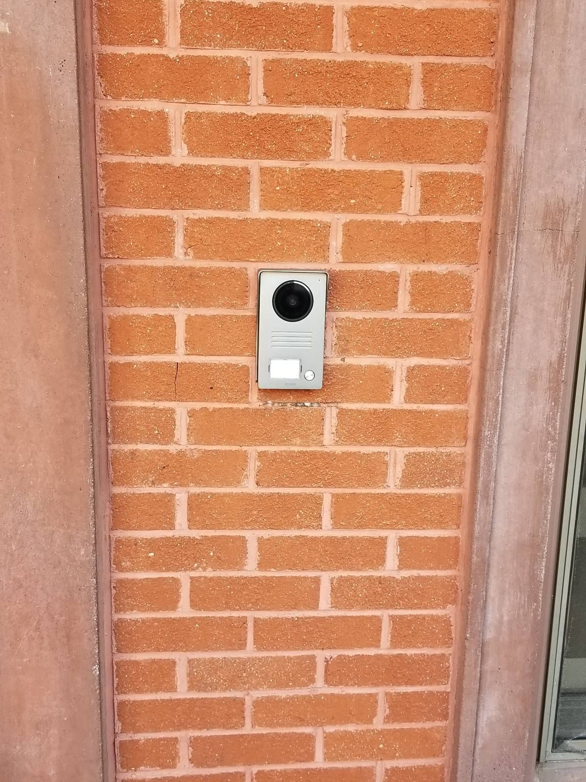 Elvox video intercom door station surface-mounted on a brick wall at a Brooklyn apartment building entrance