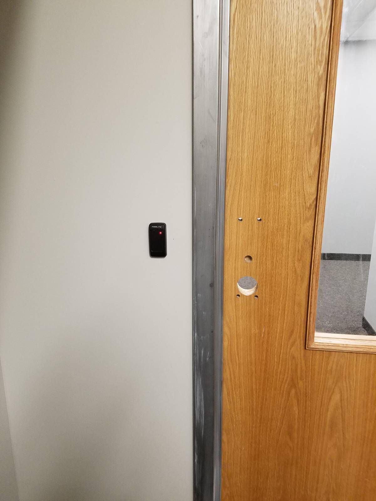 Proximity card reader beside a wood door prepared for new hardware at a West Orange, NJ church