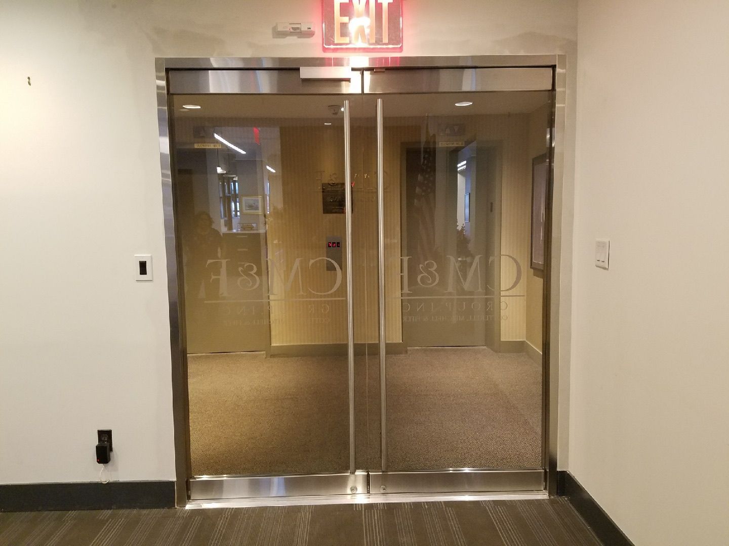 Close-up interior view of Herculite door hardware and glass panel detail at CM&F Group Manhattan office